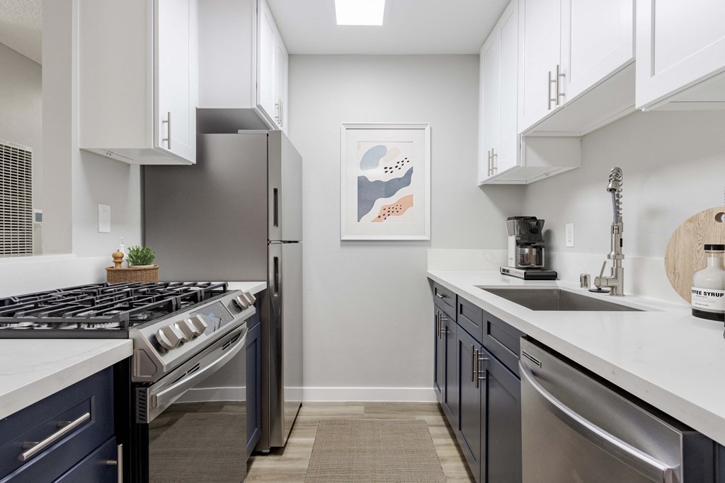 an open kitchen with stainless steel appliances and white counter tops