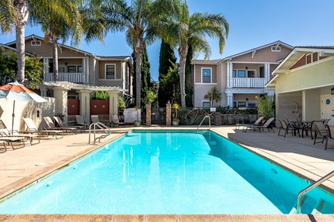 2-Bedroom Apartments in Ventura, CA - Ralston Courtyards - Pool With Spacious Sundeck, Lounge Chairs, Umbrellas, And Palm Trees.