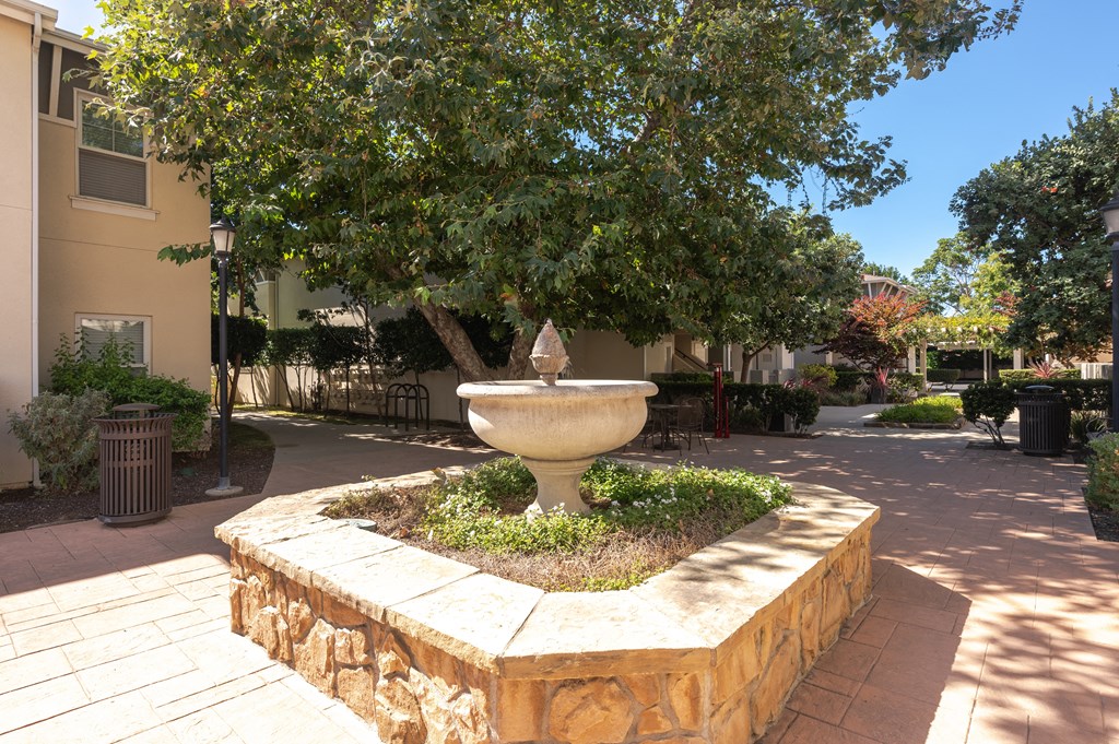 a fountain in the middle of a courtyard with a tree