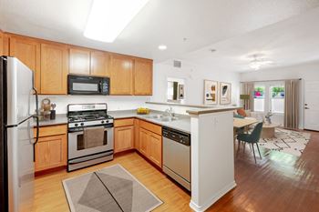 the kitchen and dining area of a house with wooden cabinets and stainless steel appliances