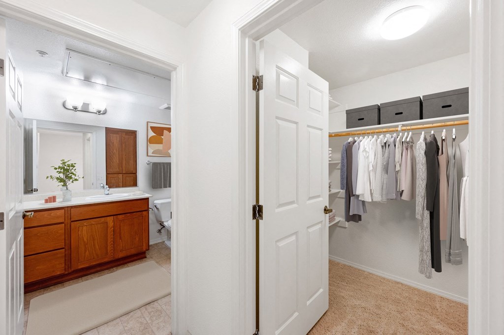 a bathroom with a white door and a closet full of clothes