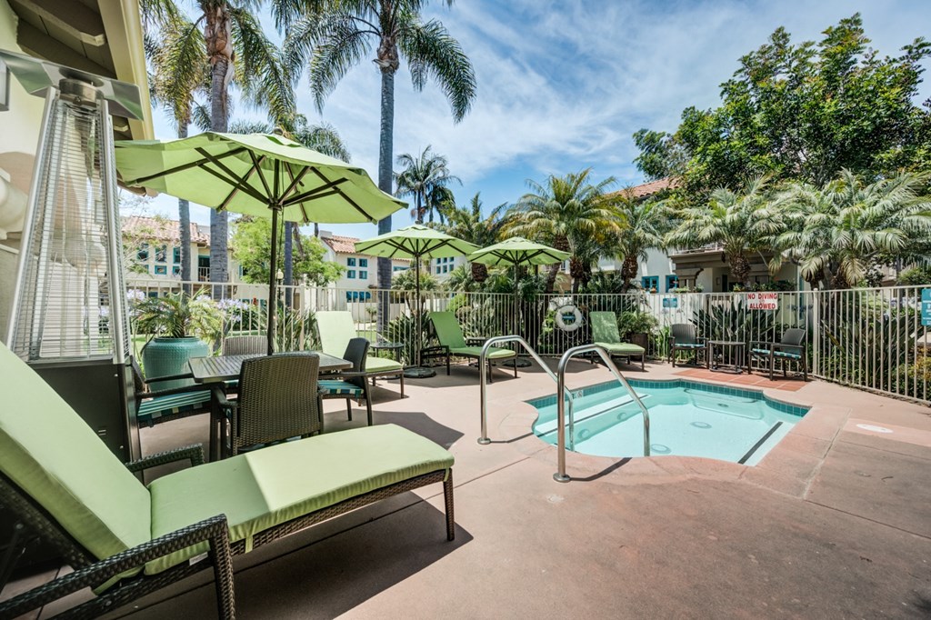 1-Bedroom Apartments in Santa Barbara, CA - Rancho Franciscan - Hot Tub, Green Lounge Seats, Green Umbrellas with Tables and Chairs, Lush Landscaping, and Standing Outdoor Glass Tube Patio Heater