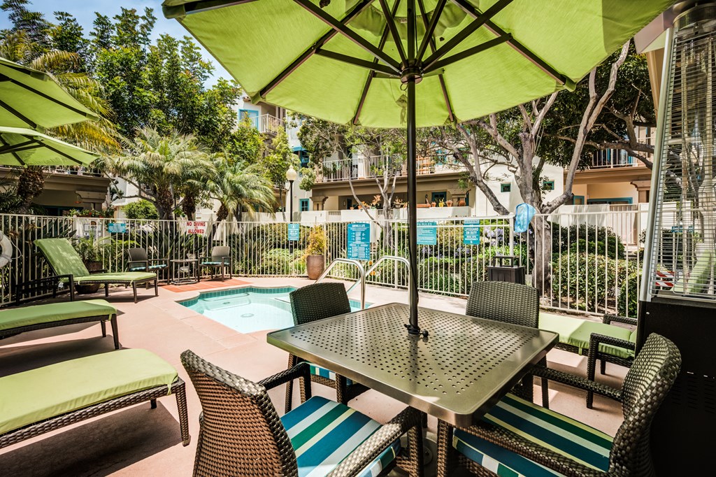 a patio with a table and chairs and a pool in the background