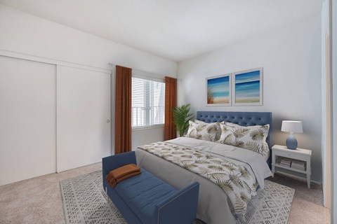 Assisted Living in Santa Barbara, CA - Rancho Franciscan - Bedroom with Carpet Flooring, Large Bed, Bed Bench, Nightstand with Lamp, Sliding Closet Doors, and Large Window.