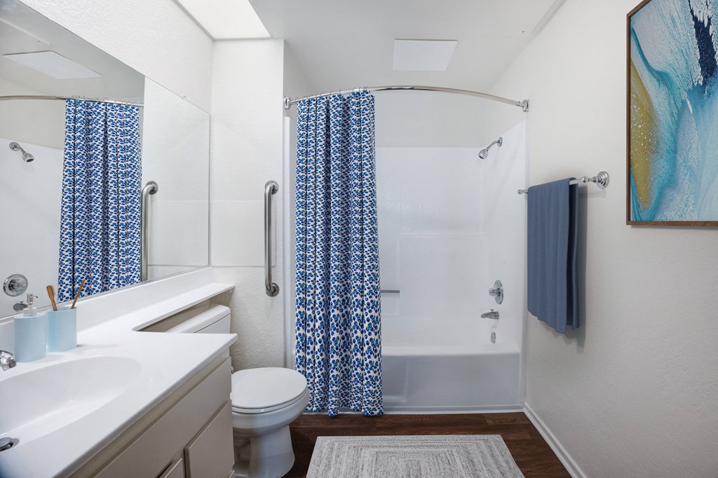 a bathroom with a white sink and toilet and a white shower with a blue shower curtain