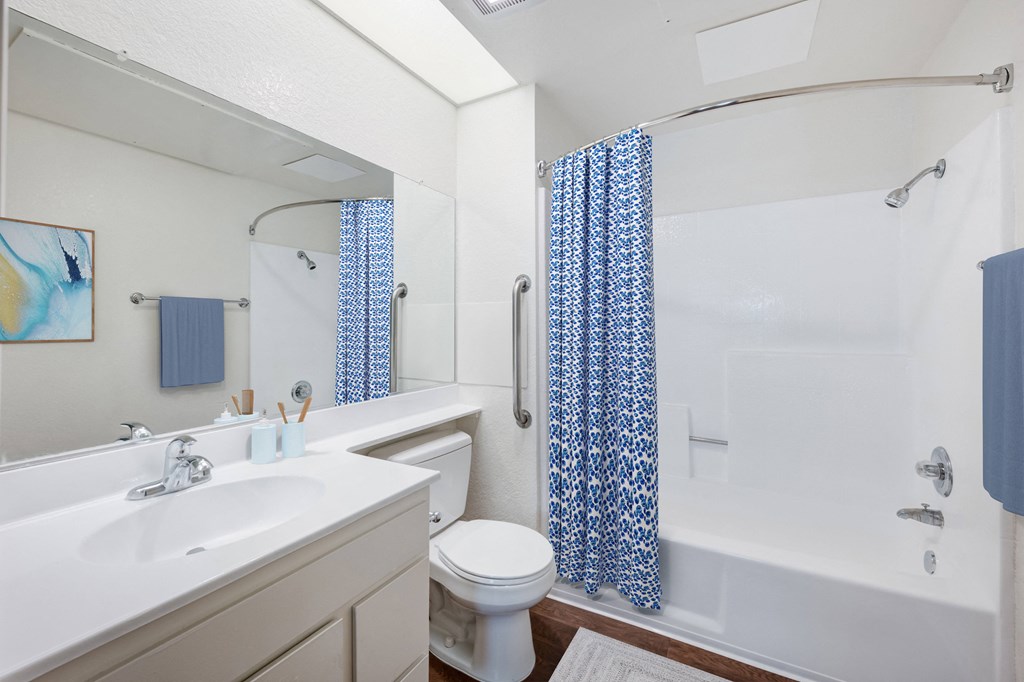 a bathroom with a white sink and tub and a white toilet with a blue shower curtain