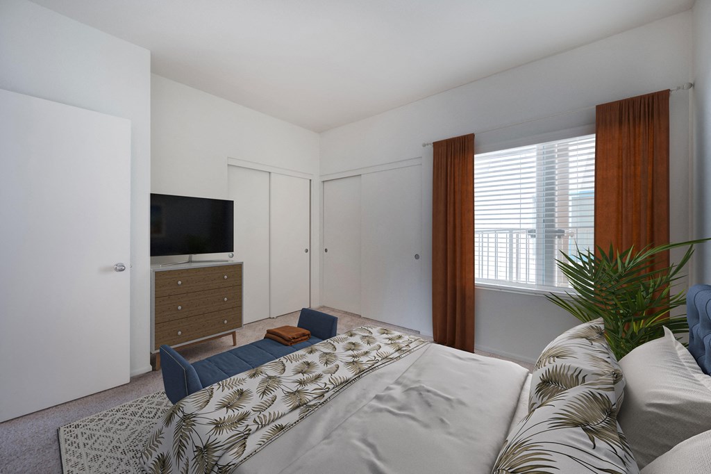One-Bedroom Apartments in Santa Barbara, CA - Rancho Franciscan - Bedroom With Bed, Carpeting, Two Large Closets, Dresser, TV, Bench, and Large Window With Blinds and Coverings
