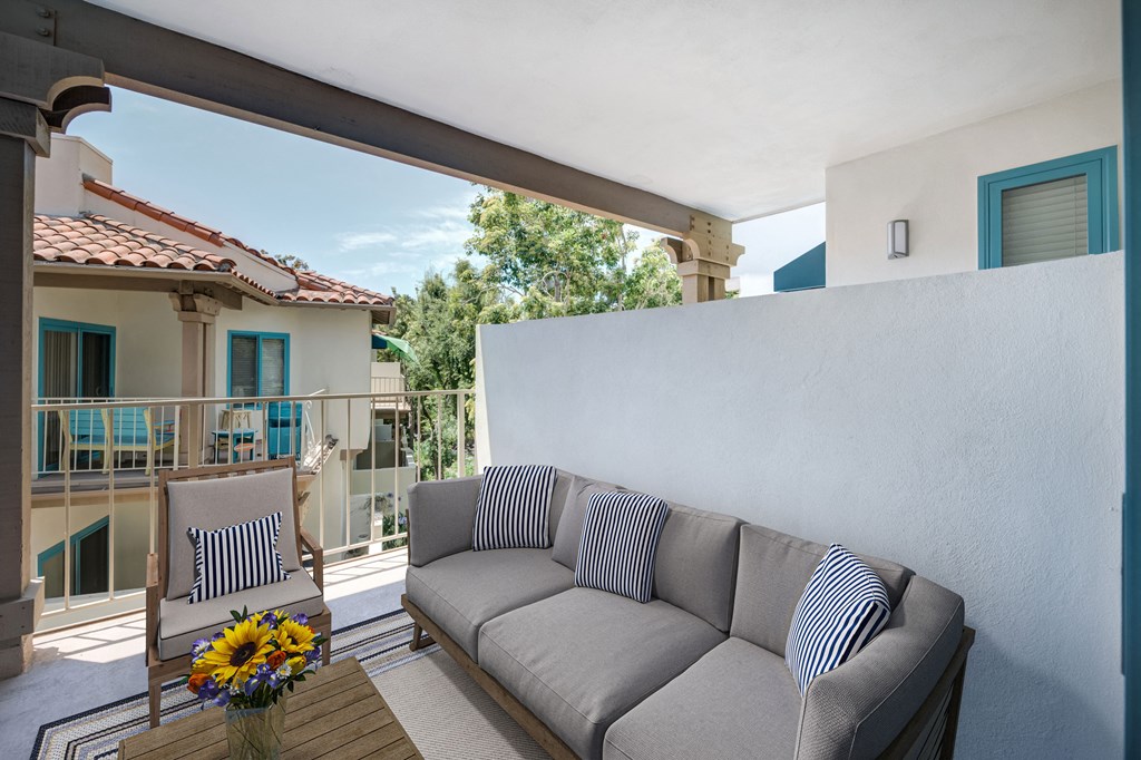 a couch on a balcony with a vase of flowers