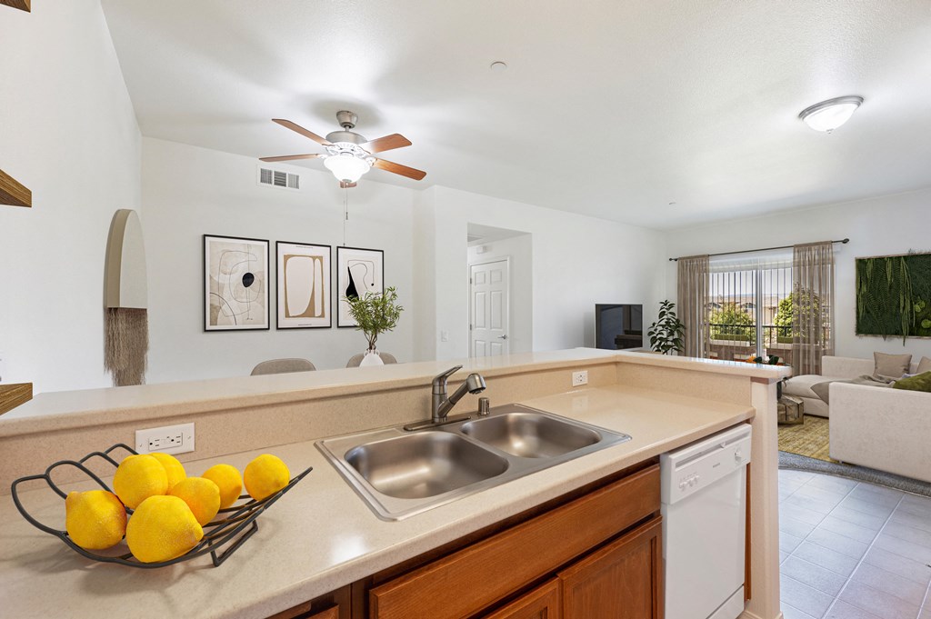 Santa Maria, CA Apartments Near Walmart - Siena - Kitchen with High Countertop, Dual Sinks, Dishwasher, Brown Cabinets, and View of Dining Area and Living Area.