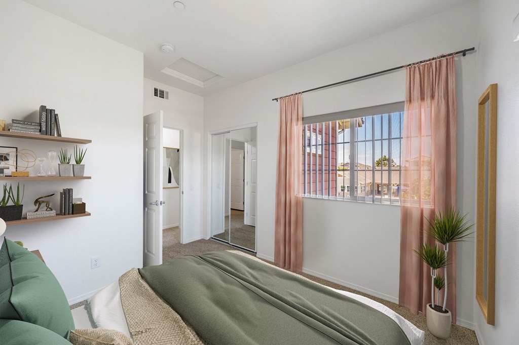 Santa Maria, CA, Apartments Near Target - Siena - Bedroom with Carpeted Floor, Bed, Floating Shelves with Books and Decors, Mirrored Closet, and Large Window with Shades