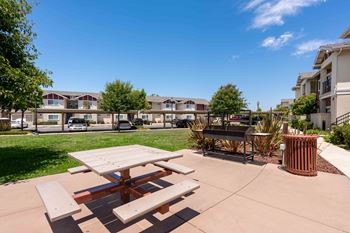 a picnic table and a trash can in front of an apartment building
