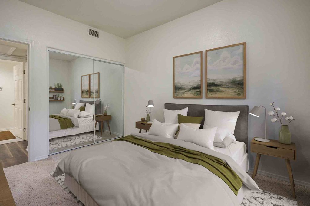 1 BR Apartments in Goleta CA - Sumida Gardens - Furnished Bedroom with Carpeted Flooring,  Large Bed, Two Nightstands with Lamps, Framed Wall Art, and Large Closet with Sliding Door Mirror