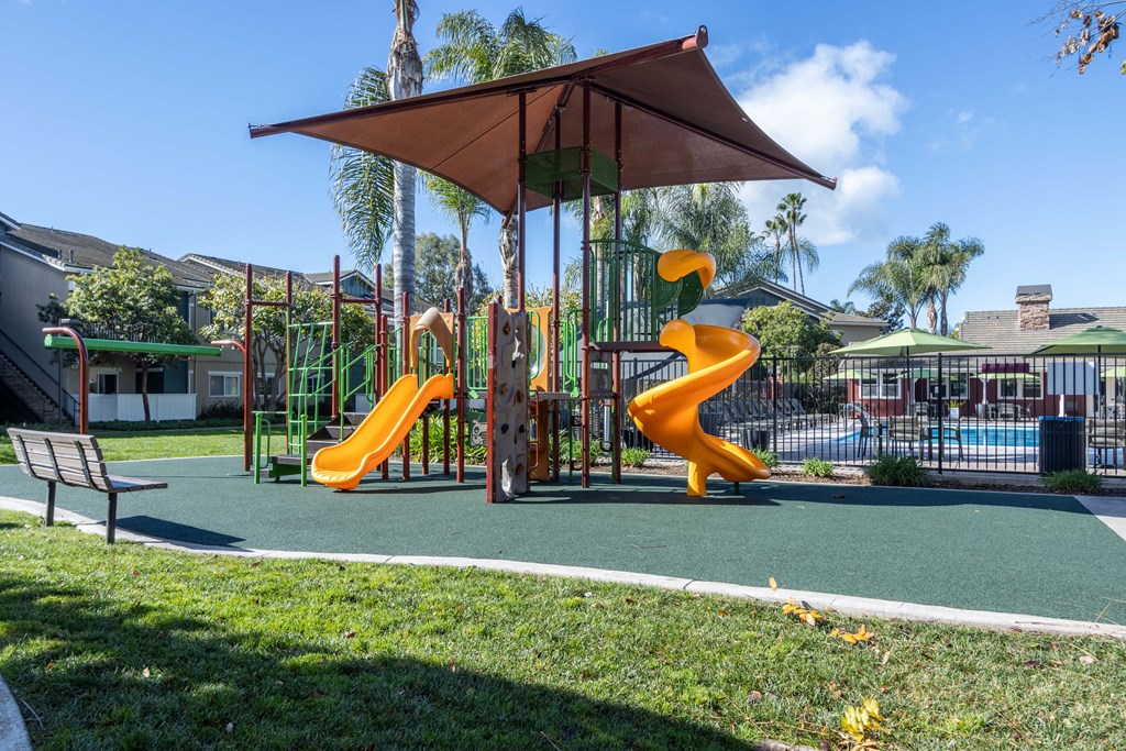 a playground with two slides and an umbrella in a park