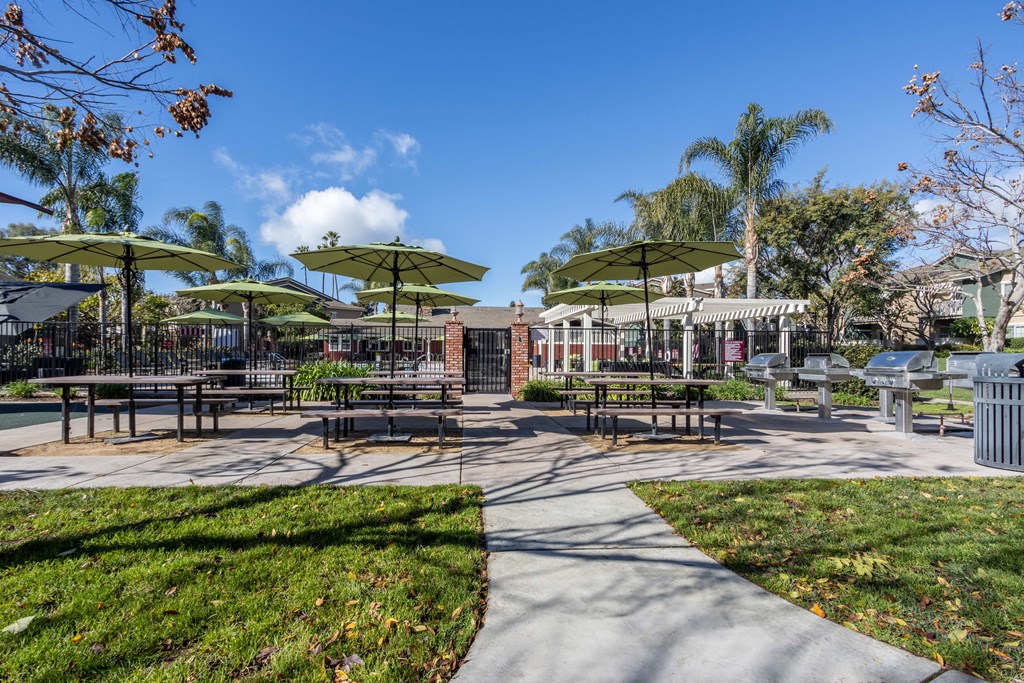 a picnic area with tables and umbrellas in a park