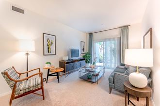 Goleta, CA Apartments-Sumida Gardens-Living Room with Carpet Flooring, High Ceilings, and Glass Sliding Door to Patio