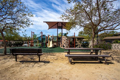 One-Bedroom Apartments in Goleta, CA - Willow Springs - Playground Area with a Large Jungle Gym, Artificial Turf, Table, Bench Seating, and Trees.