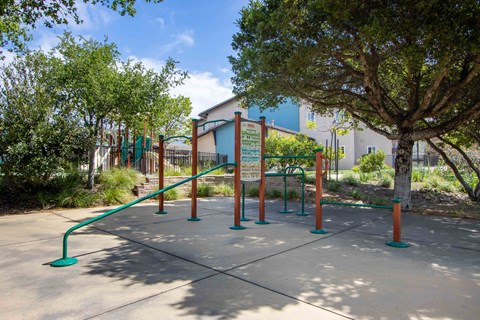 a playground in a park with trees and a building