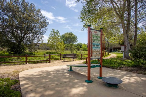 a park with a sign and benches and trees