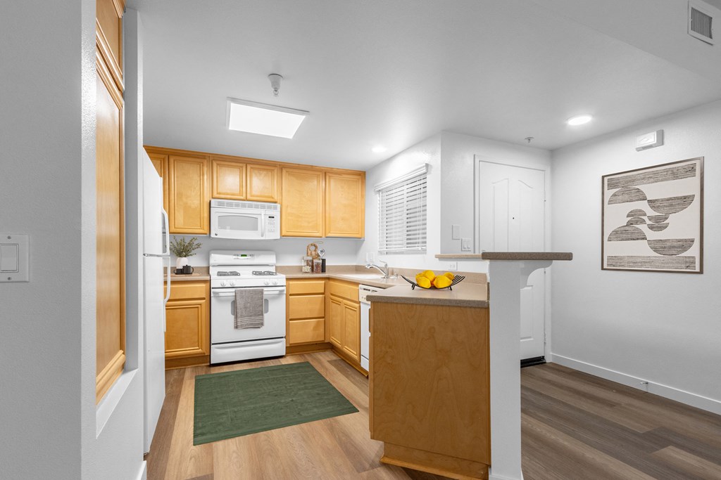 Goleta, CA, Apartments Near Starbucks - Willow Springs - Kitchen with Wood-Style Flooring, Breakfast Bar, Tan Cabinets and White Appliances