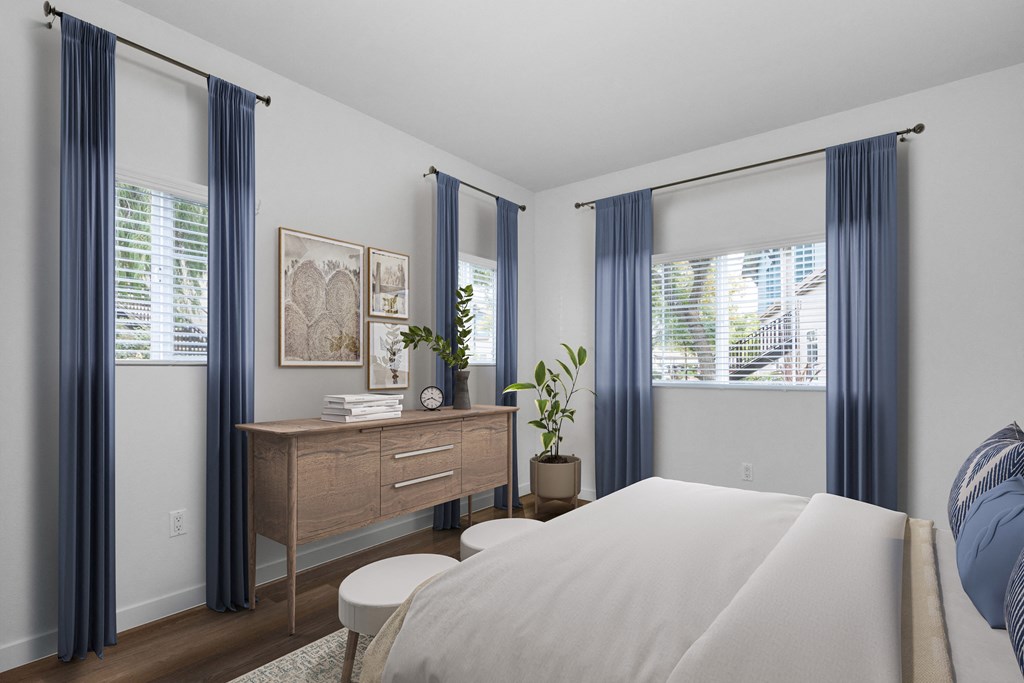 a bedroom with a large bed and two windows with blue curtains