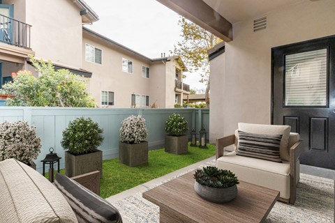 a patio with a couch and a table and plants