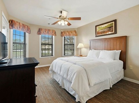 A bedroom with a large bed and a ceiling fan.
