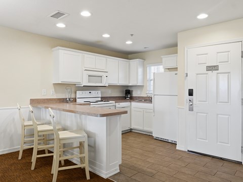 A kitchen with white cabinets and a wooden island.