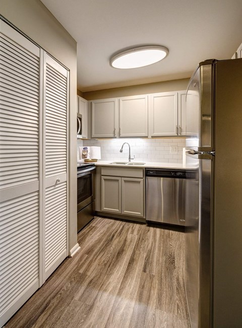 A modern kitchen with wooden floors and stainless steel appliances.