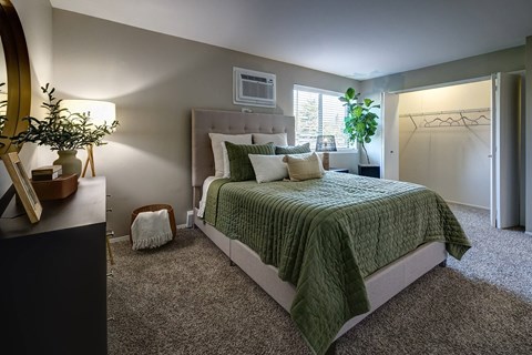 A bedroom with a bed, nightstand, and a mirror.