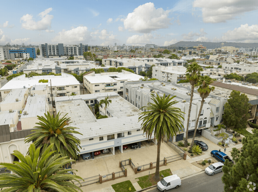 arial view of a large white building with white roofs and palm trees in front of it