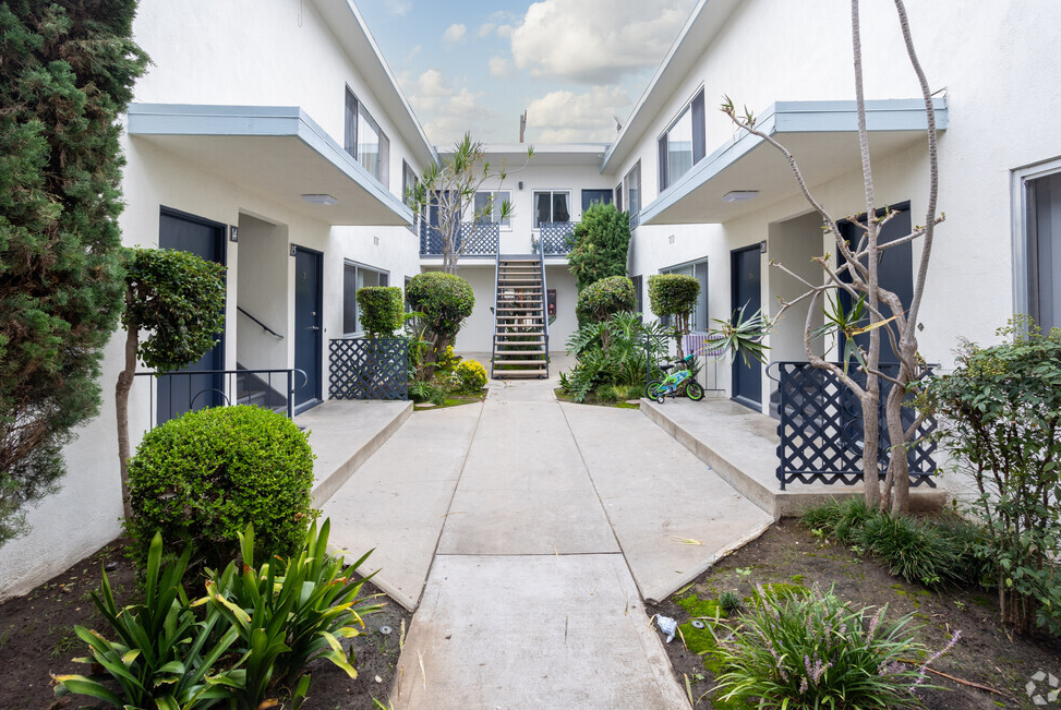 an apartment with white walls and a concrete walkway with a staircase in front of it