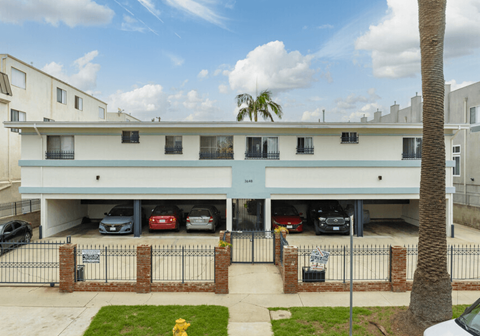 A building with a white and blue facade has a parking garage underneath it.