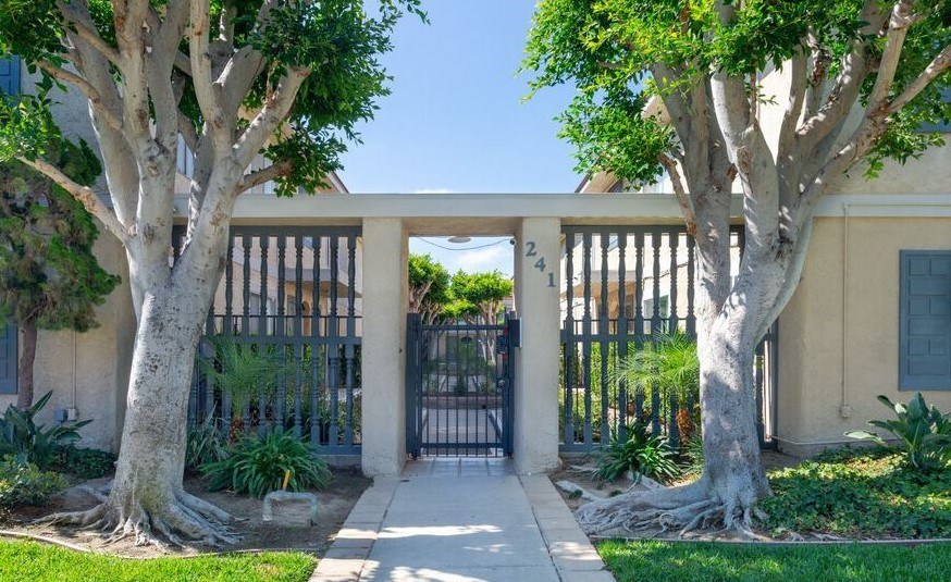 A house with a gate and trees in front.