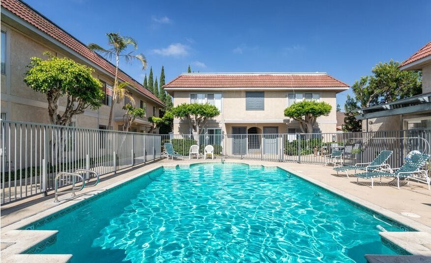 A swimming pool surrounded by a metal fence and chairs.