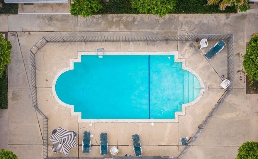 A rectangular pool with a rounded end and a spacious deck area with sun loungers.