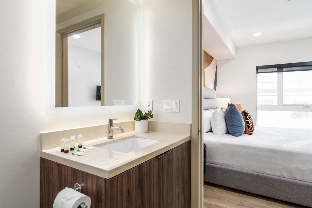 a bathroom with a sink and a mirror next to a bed at Lido Apartments - 1532 Brockton Ave, California, 90025