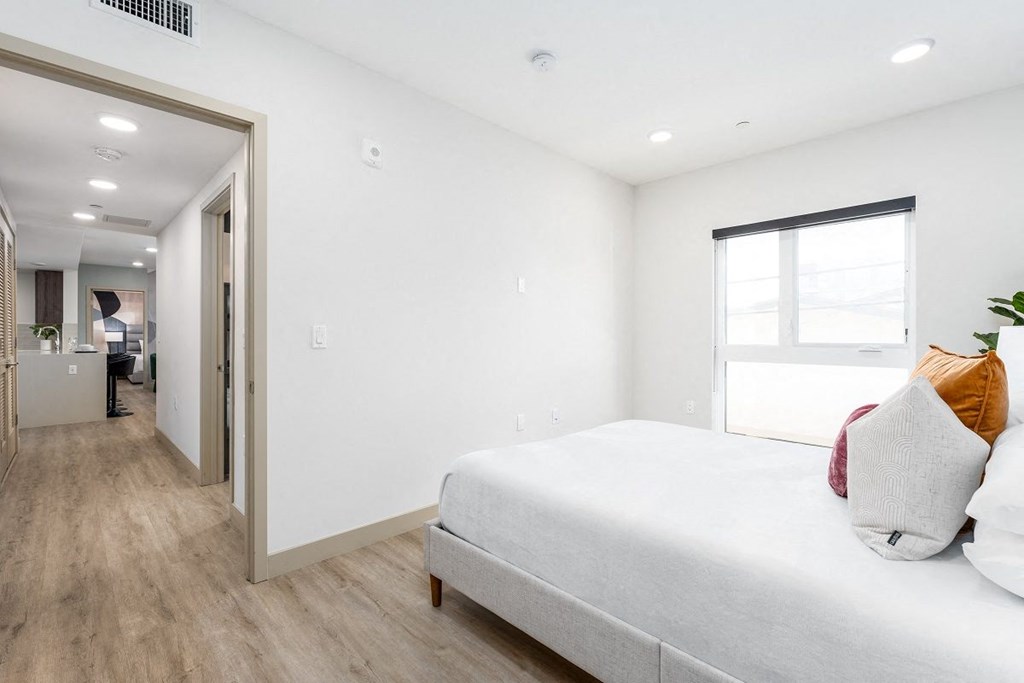 a bedroom with a large white bed and a door to a hallway at Lido Apartments - 1532 Brockton Ave, California