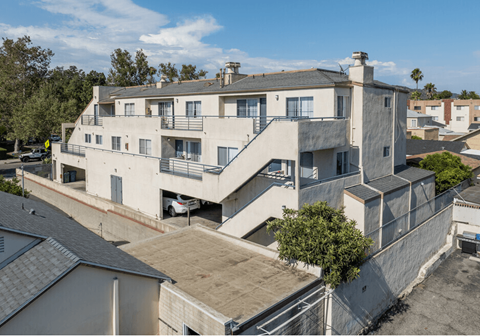 an aerial view of a large white apartment building with balconies and a staircase