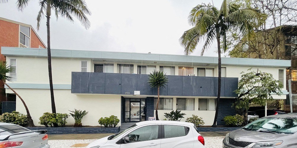 a building with a black roof and palm trees in front of it