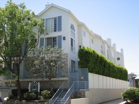 A white building with a green hedge on the side.
