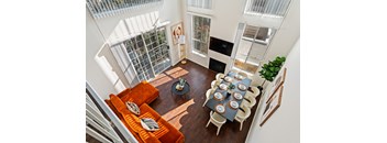 A dining room with a table set for six with orange cushions on the couch.