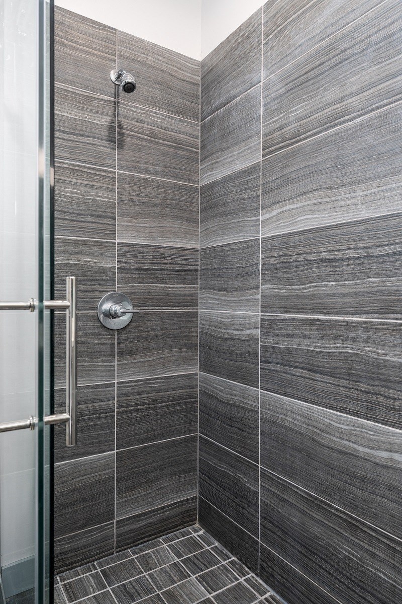 a tiled bathroom with a shower and a glass door at Lido Apartments - 4025 Grandview, California, 90066