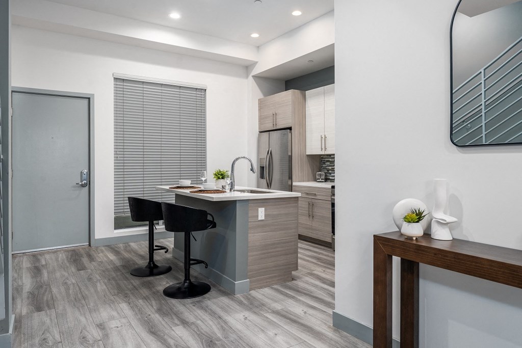 a kitchen with an island and a bar with two black stools at Lido Apartments - 4025 Grandview, Culver City, 90066