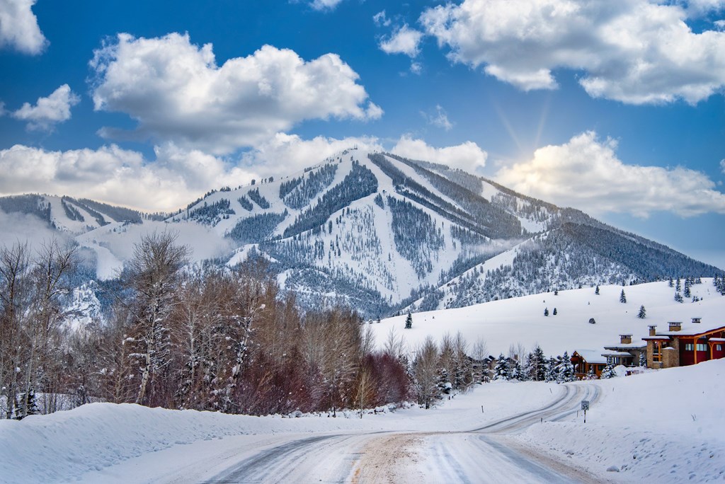 A snowy mountain landscape with a road leading towards a house.