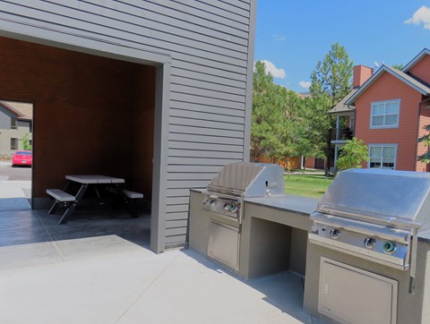 a stainless steel outdoor kitchen with a grill and a picnic table