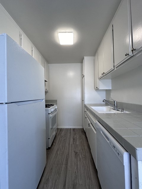 A kitchen with white appliances and cabinets.