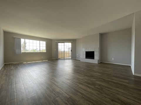 A spacious living room with a fireplace and hardwood floors.