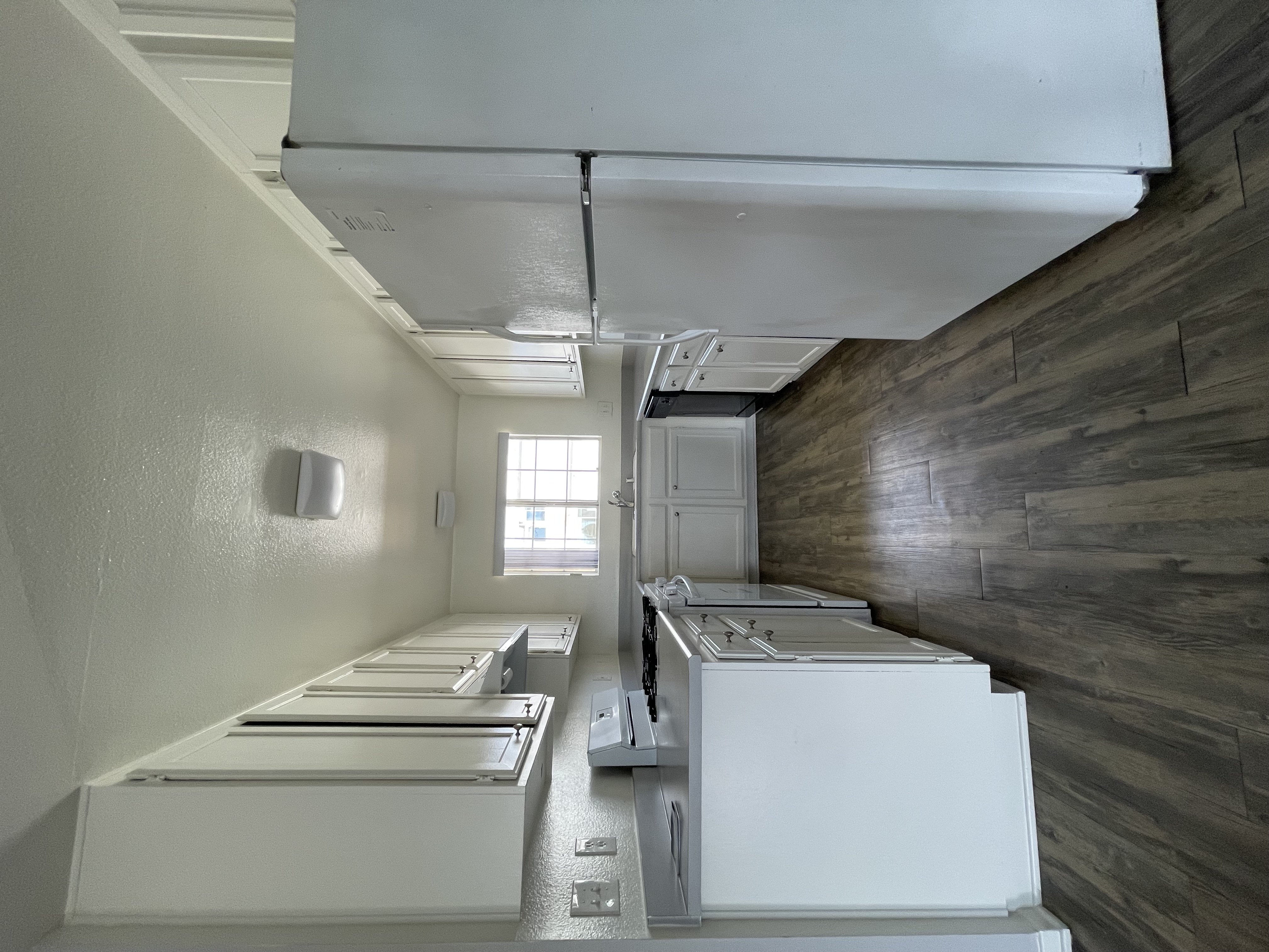 A kitchen with white appliances and wooden walls.