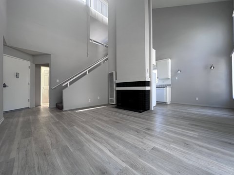 A spacious room with a staircase and a fireplace.