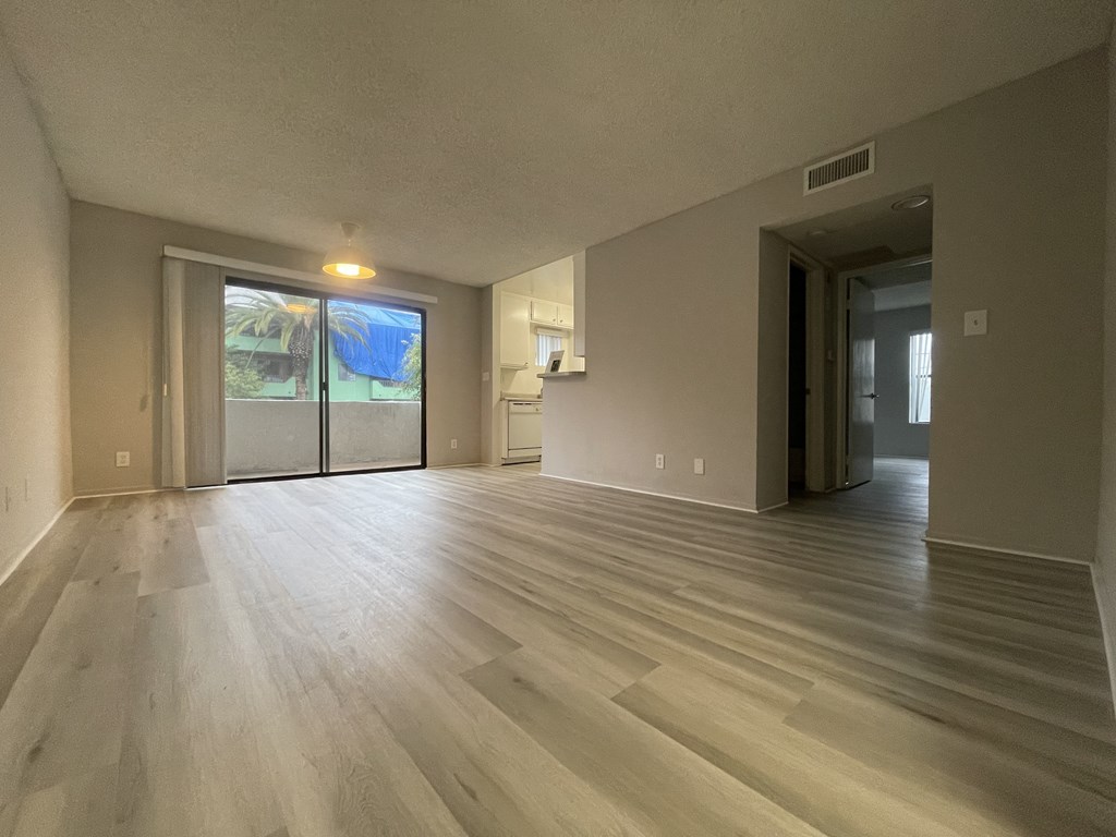 A room with light wood flooring and a sliding glass door leading to a backyard.